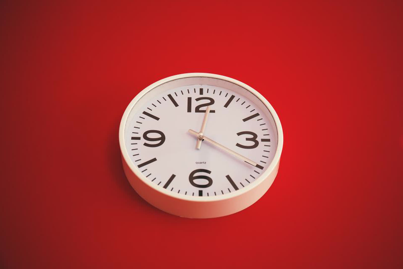 A white wall clock on a red background