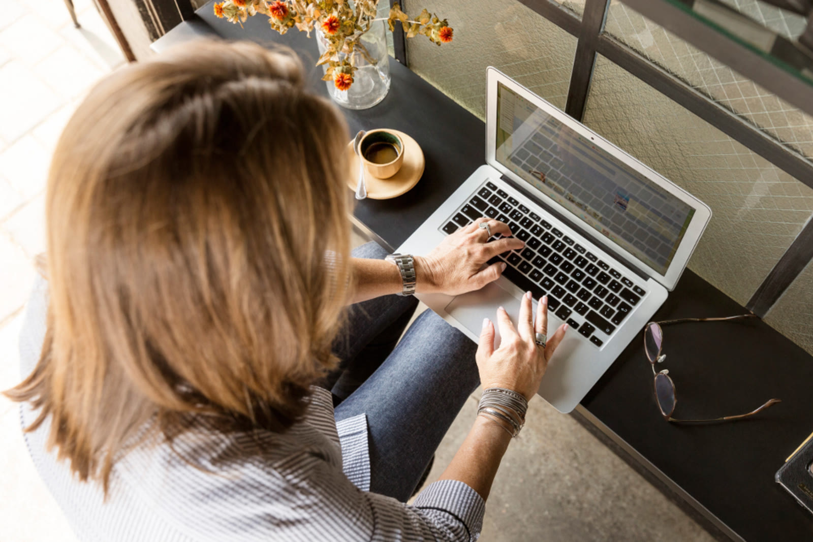 A woman typing on a laptop at a table, seen from above