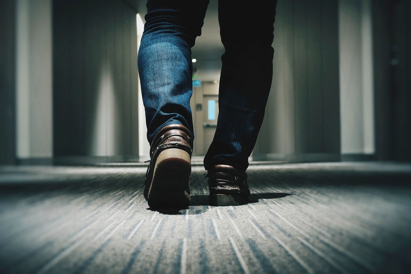 Close-up of someone's shoes as they walk down a hallway