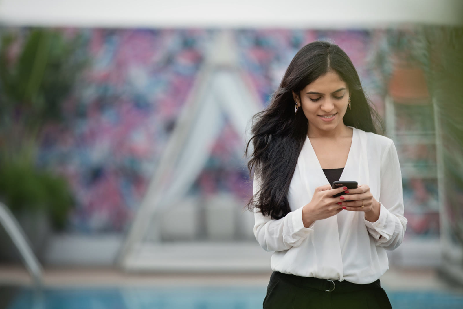 A woman smiling at her phone as she types a message