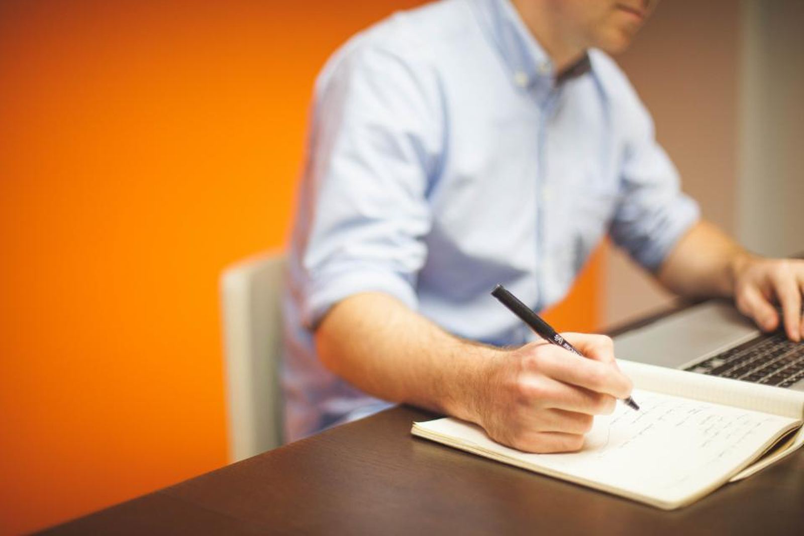 A man writing in a notebook at a desk