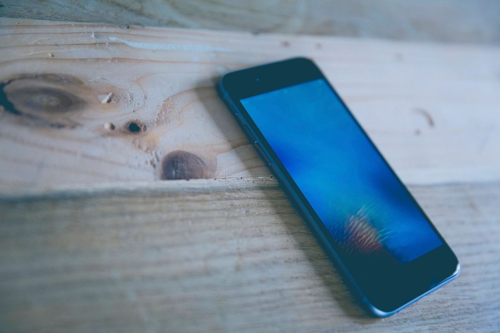 A smartphone lying face up on a wooden table