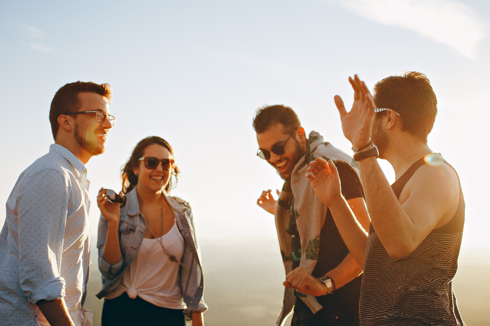 A group of friends laughing together outdoors in the sun